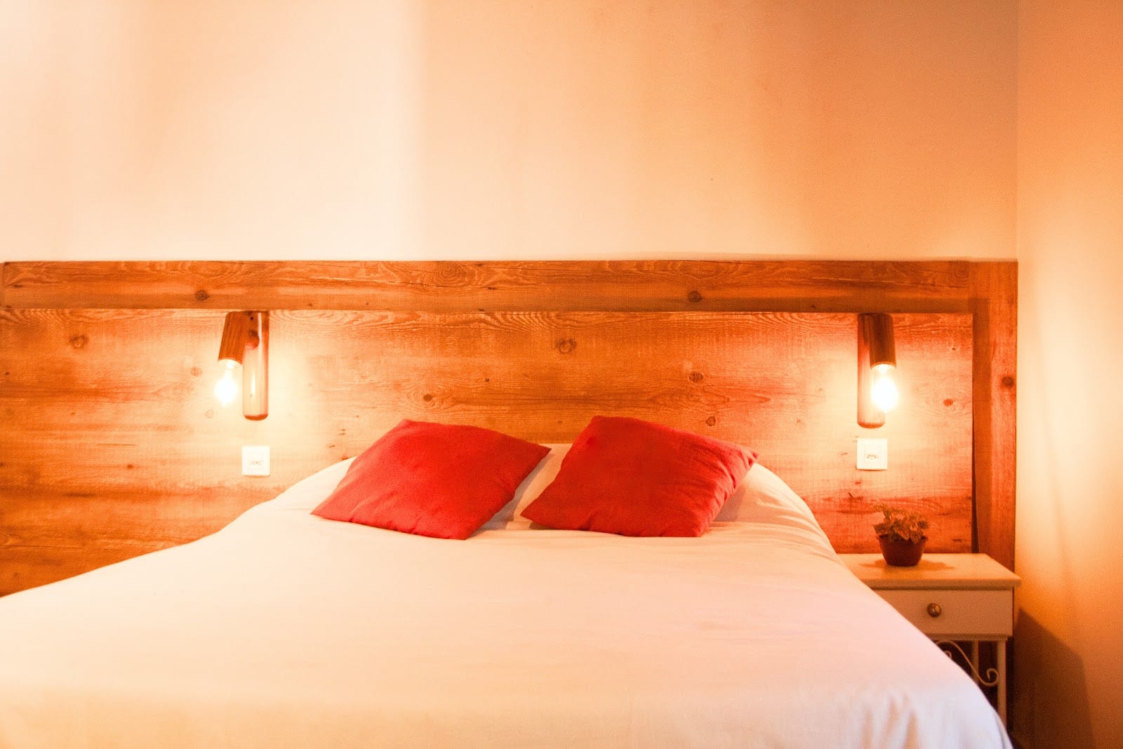 Private room with a double bed, red accent pillows and bedside lamps at Nômades Riverside, Florianópolis