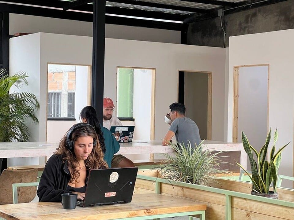 Nomads working on laptops in the bright open coworking room at Co404 Medellin
