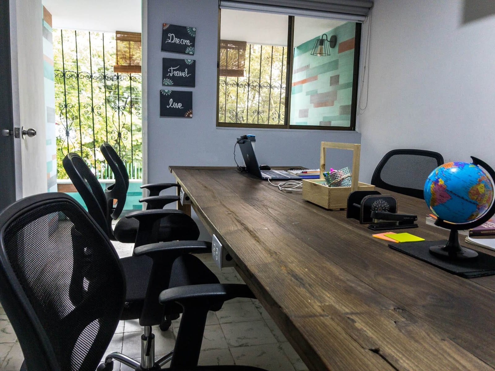 Coworking workspace at Pandora's House Coliving with mesh office chairs and a 'Dream Travel Live' wall