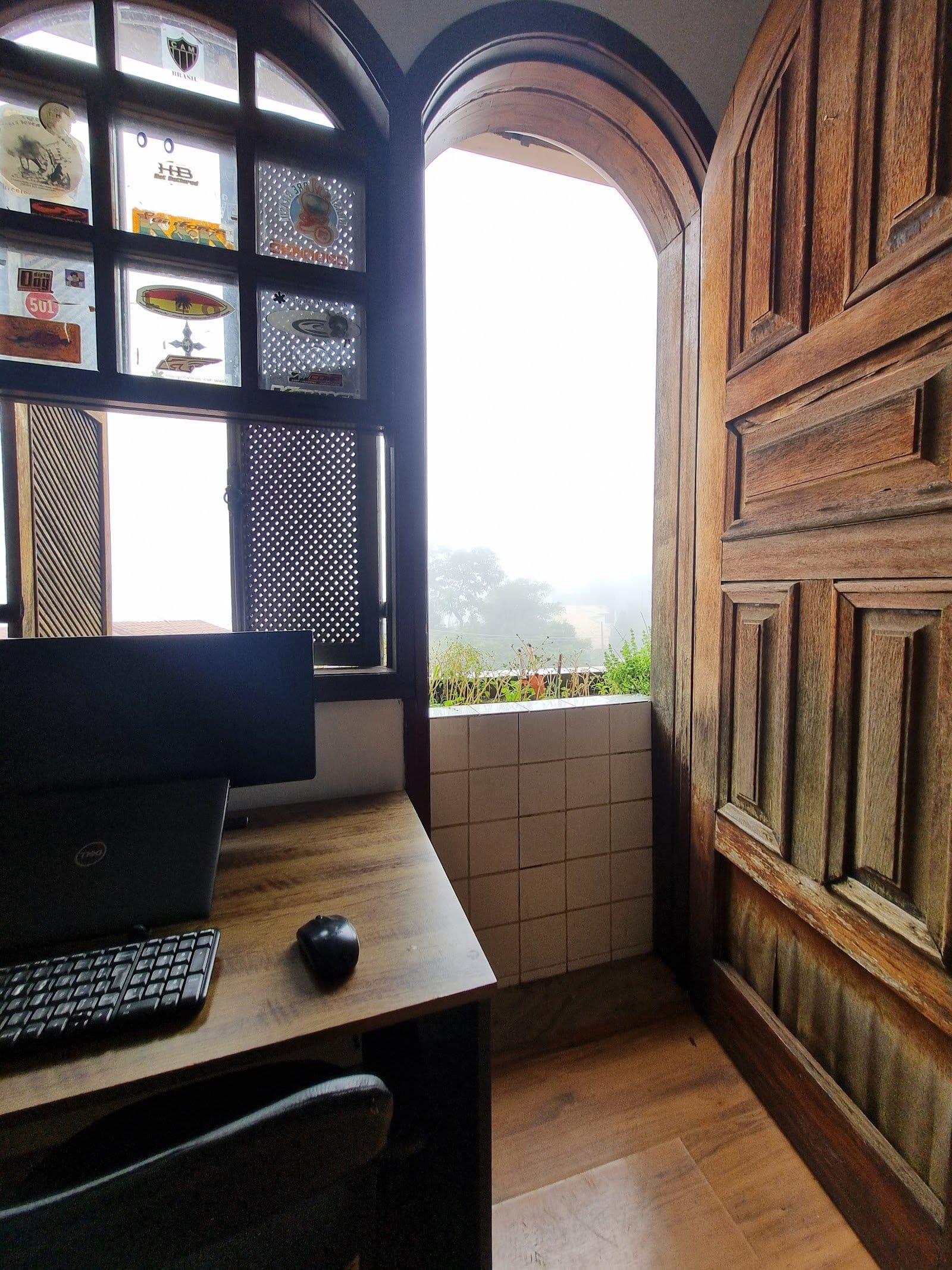 Wooden desk workspace with a laptop and garden view at Horizonte Coliving