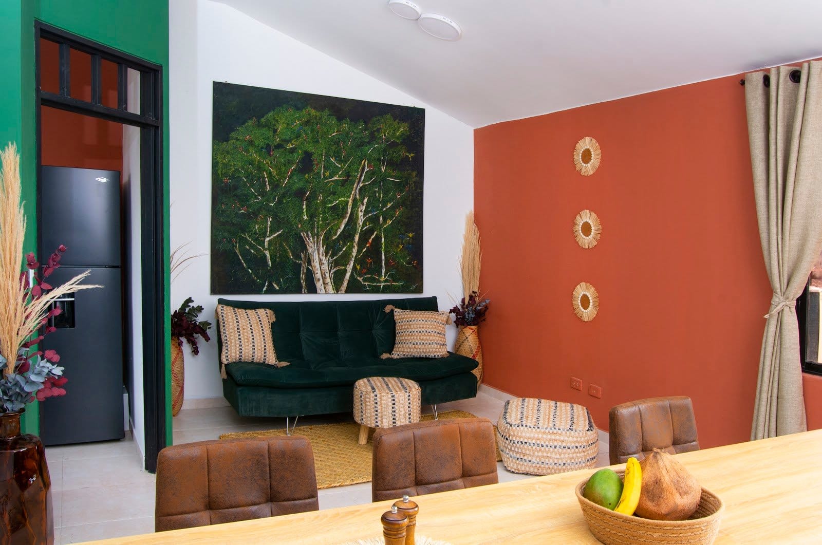 Communal lounge and dining area at Bohemia Boutique Hostel Cali with green velvet sofa and terracotta wall