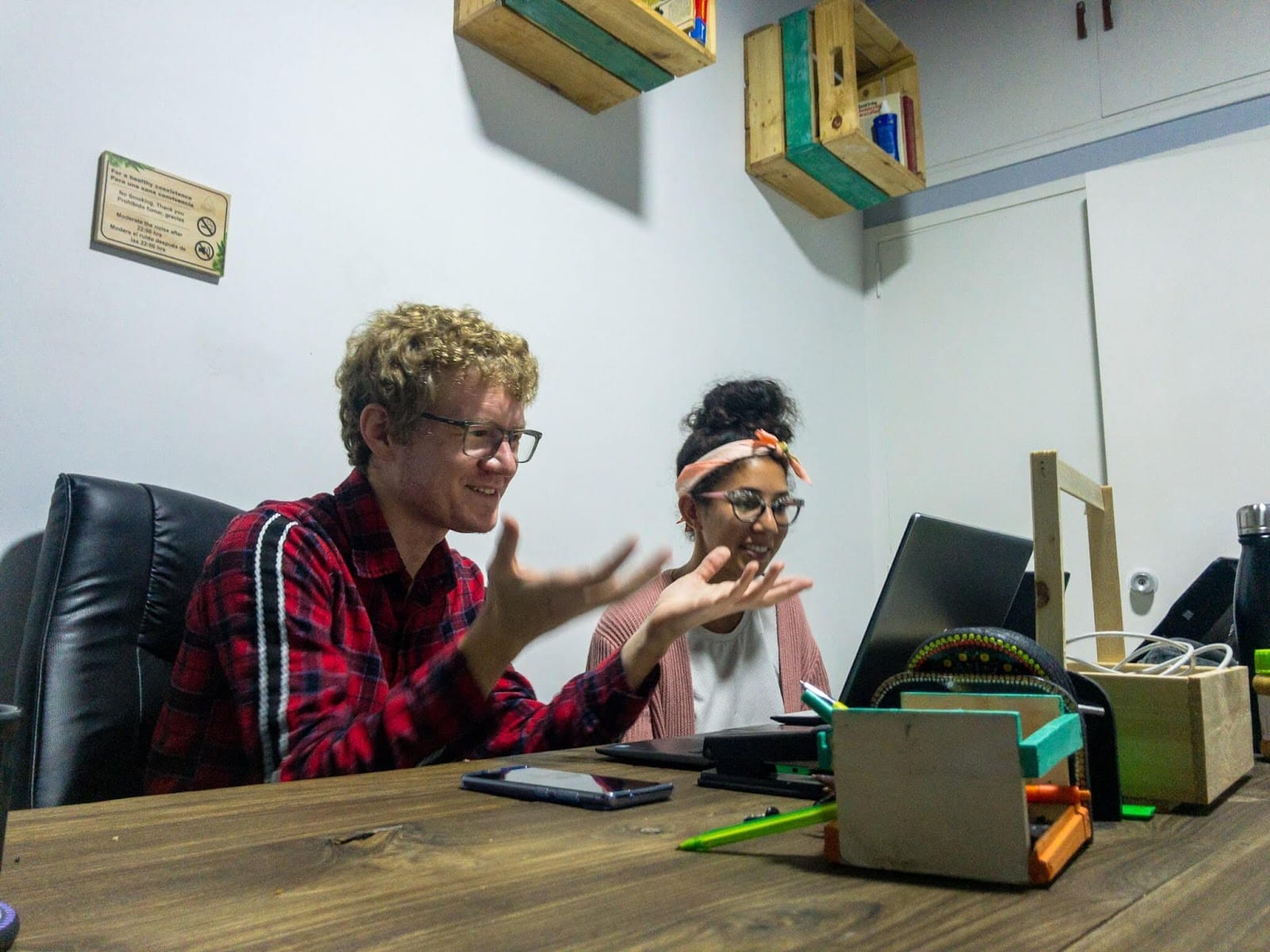 Two residents working and chatting together at the shared coworking table at Pandora's House Coliving