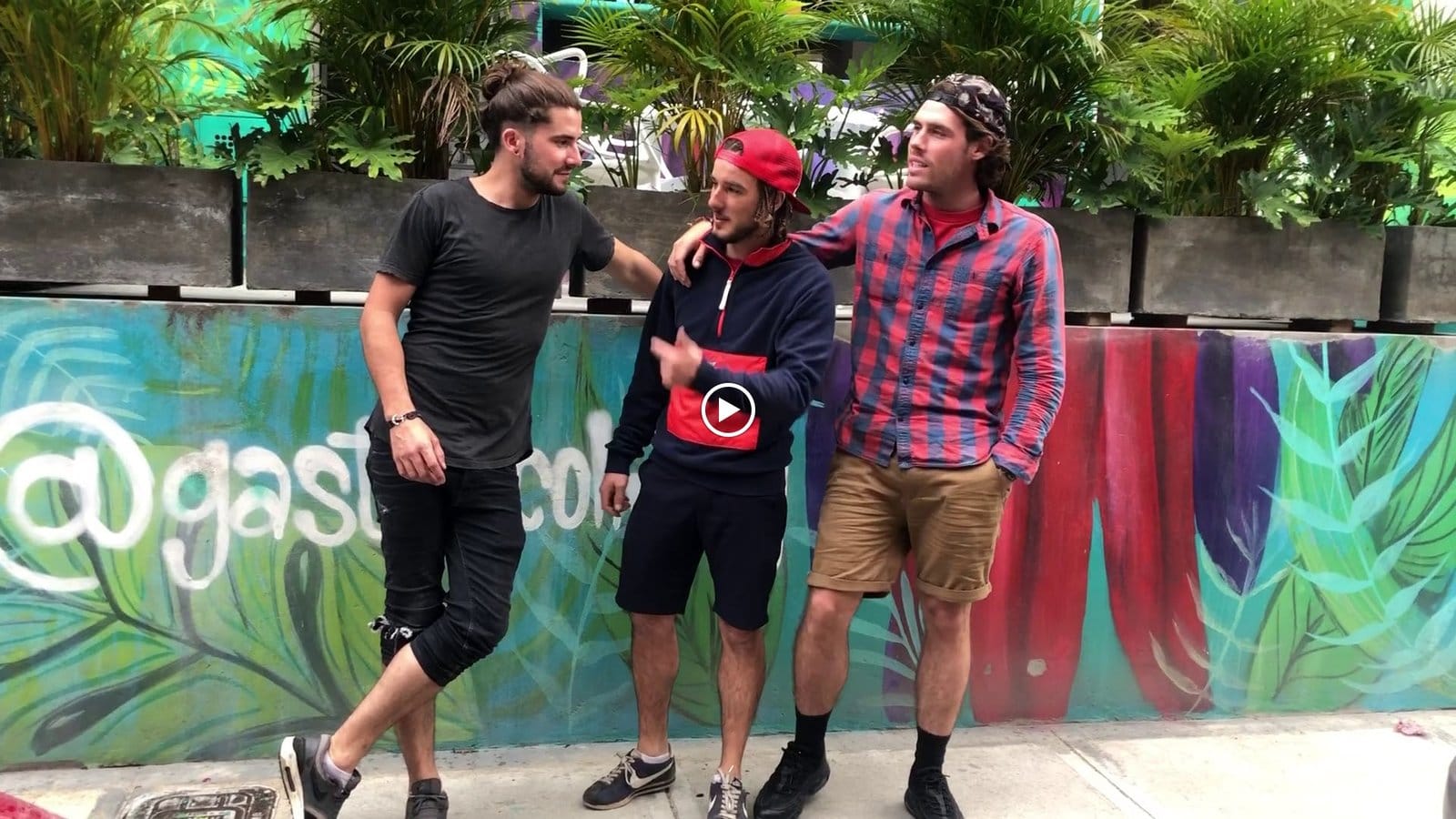 Three guests hanging out together in front of the Gastón Coliving mural