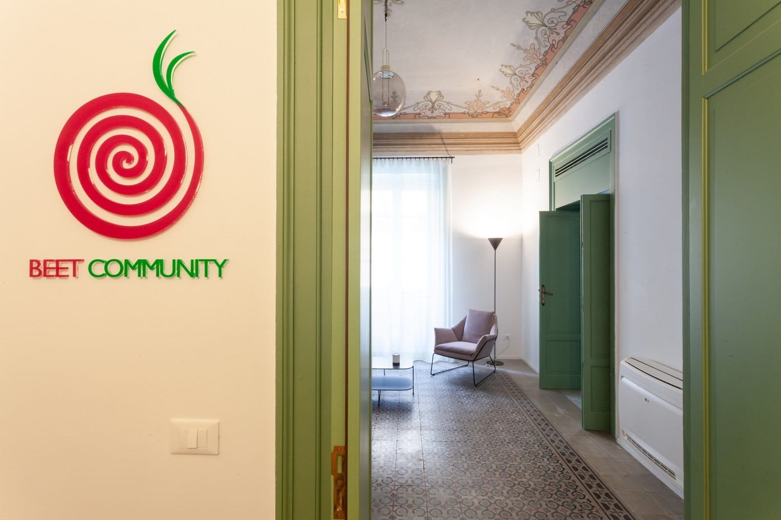 BeetCommunity entrance hall with the red beet logo opening onto a frescoed lounge in Palermo