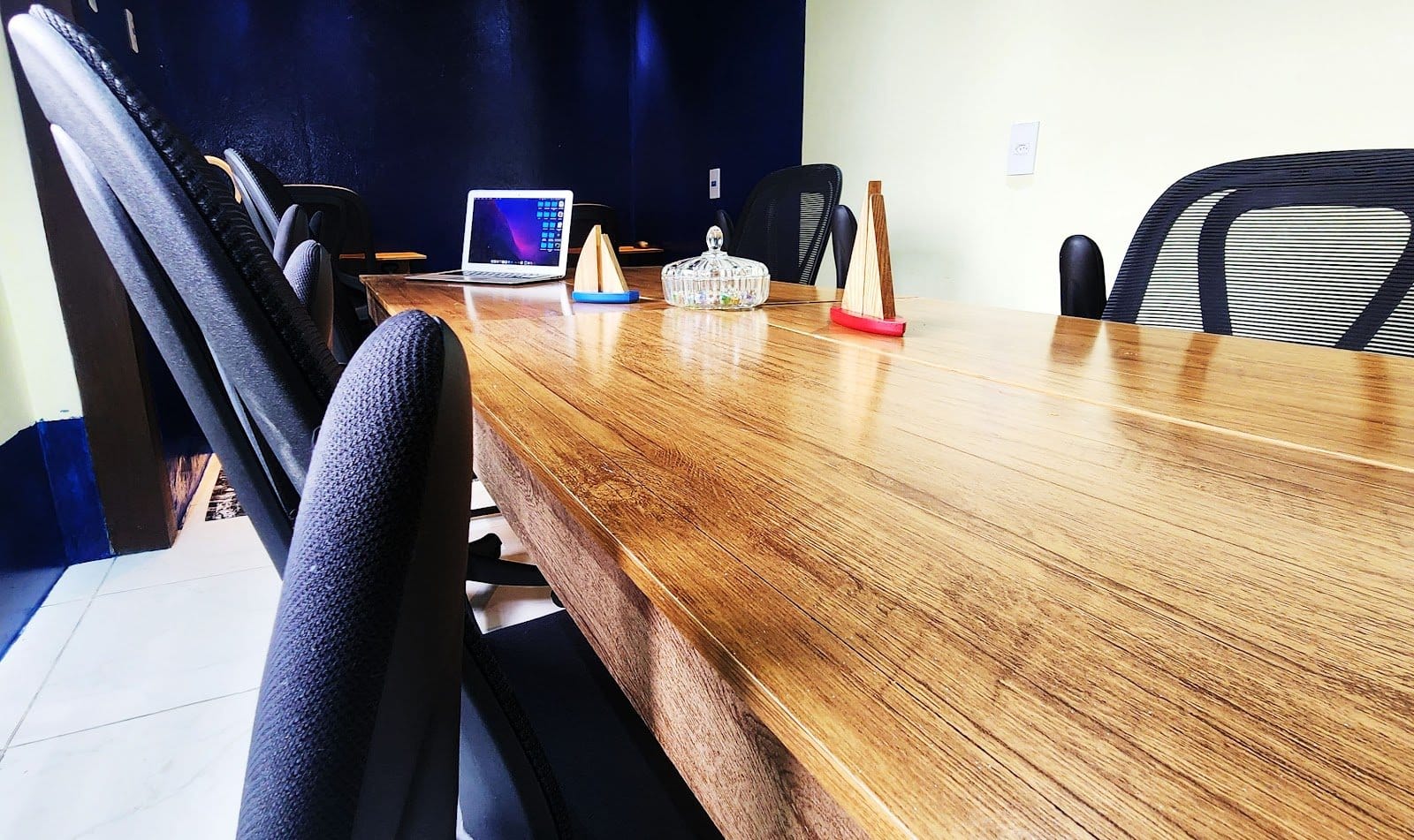 Large shared coworking table with a laptop and ergonomic chairs at Casa Maré coliving in Florianópolis