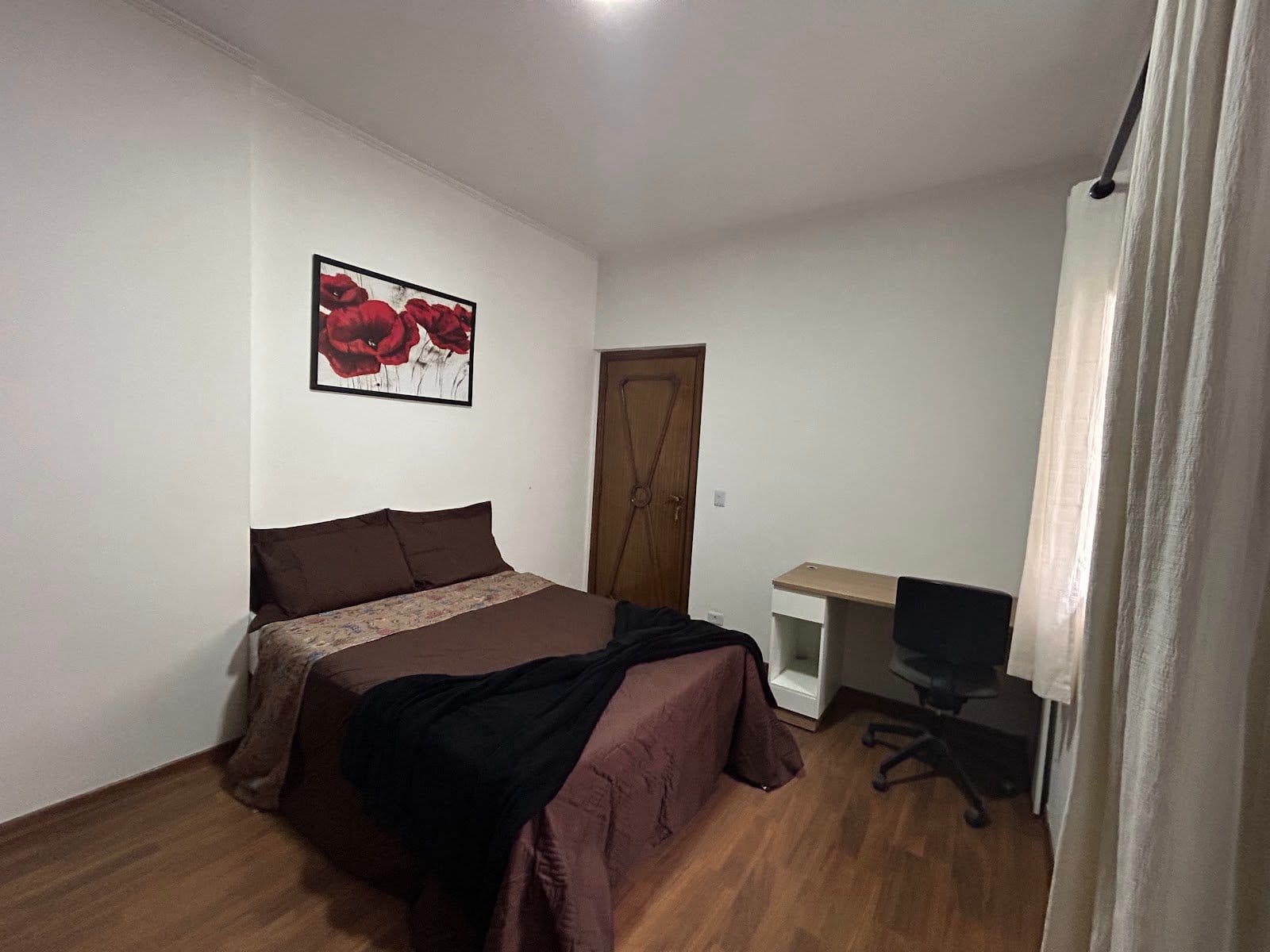 Private furnished bedroom with double bed, desk and artwork at Coliving Brooklin in São Paulo