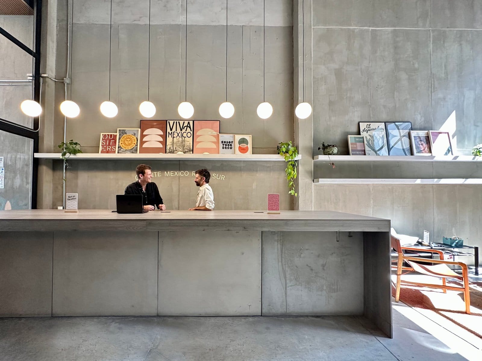 The lobby at Outsite Mexico City Roma Sur with concrete design, globe pendant lights, and curated Mexican art
