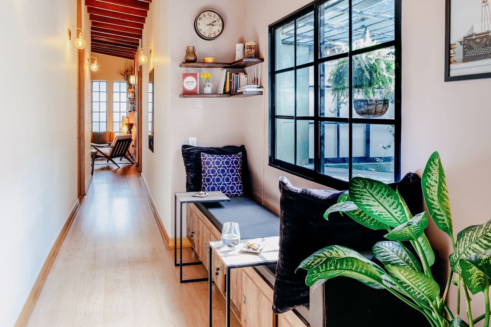 Sunlit interior hallway with a cushioned bench seat and plants at Balu Coliving Medellin