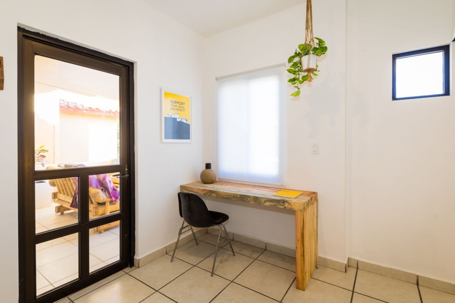 Outsite Los Cabos dedicated workspace with wooden desk, black chair and 'Support Your Local Project' Outsite poster
