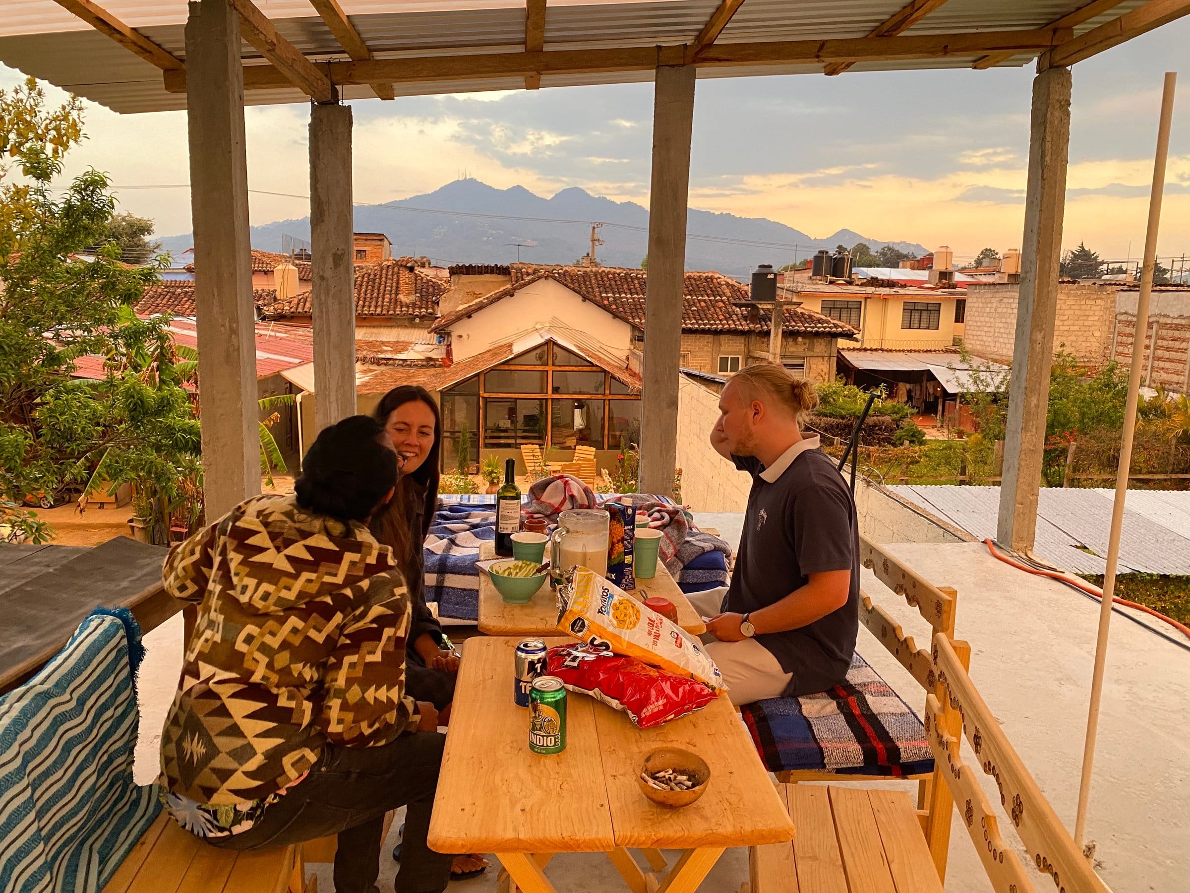 Three Co404 residents sharing a meal on the rooftop terrace with mountain views at sunset