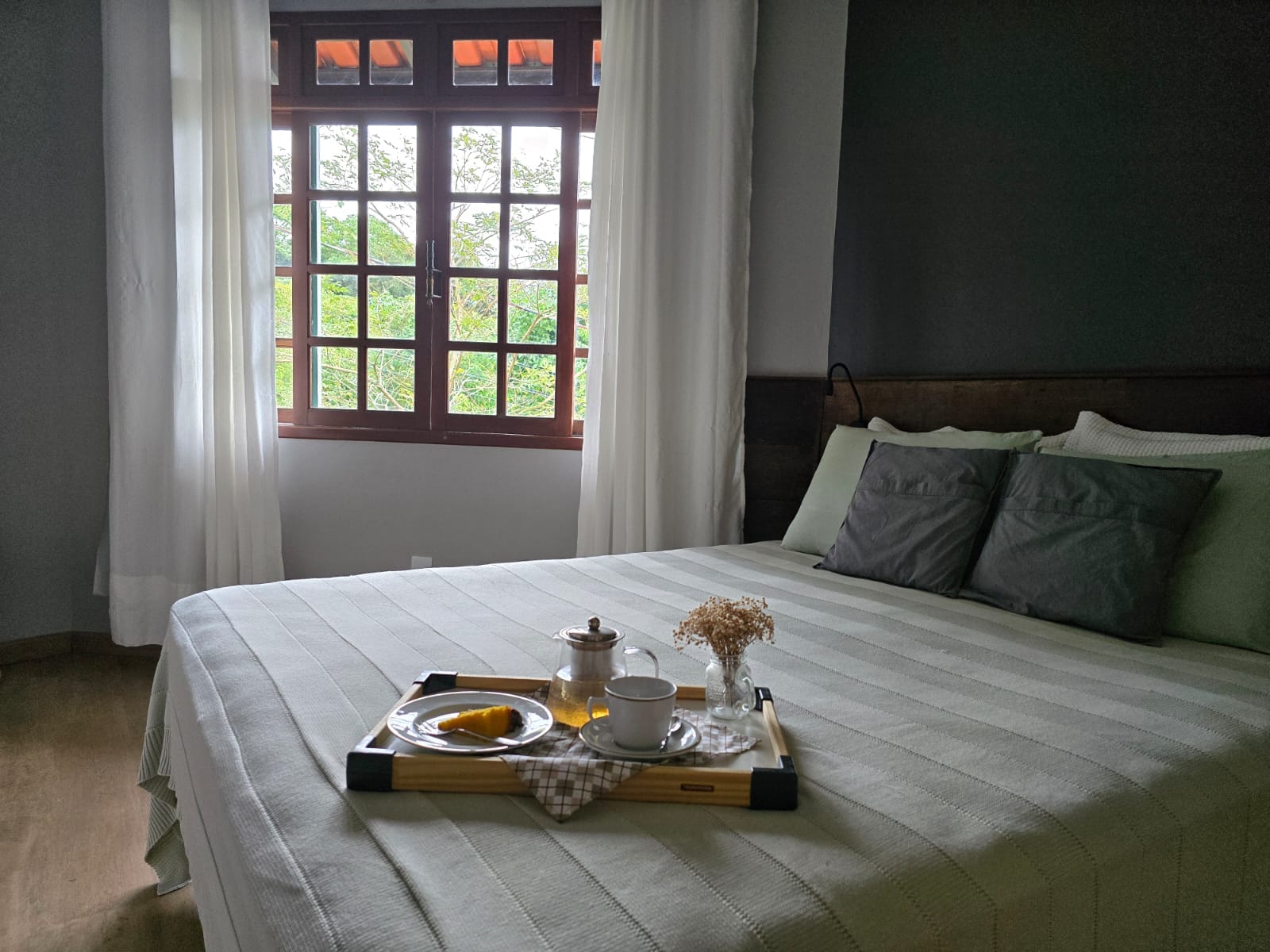 Bright bedroom with a breakfast tray on the bed and garden view through the window at Coliving Casa Jerivá