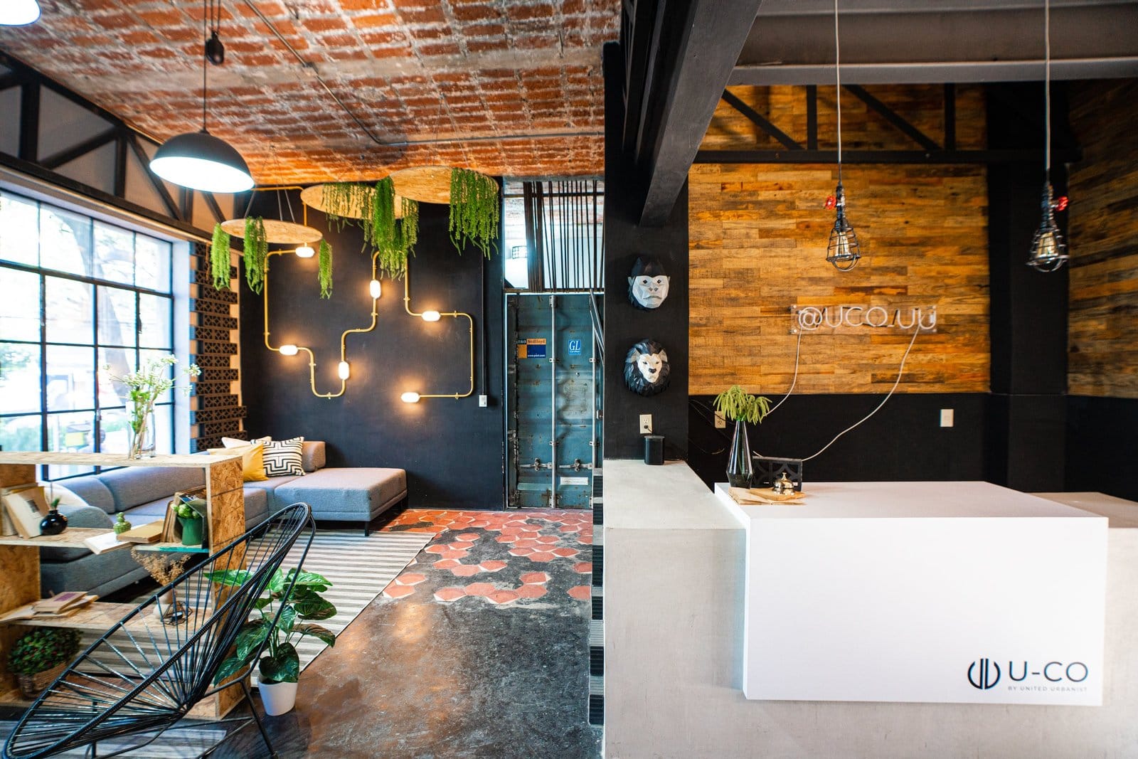 Wide view of the U-Co Roma lobby and lounge area — brick ceiling, industrial pendant lights, and branded reception desk