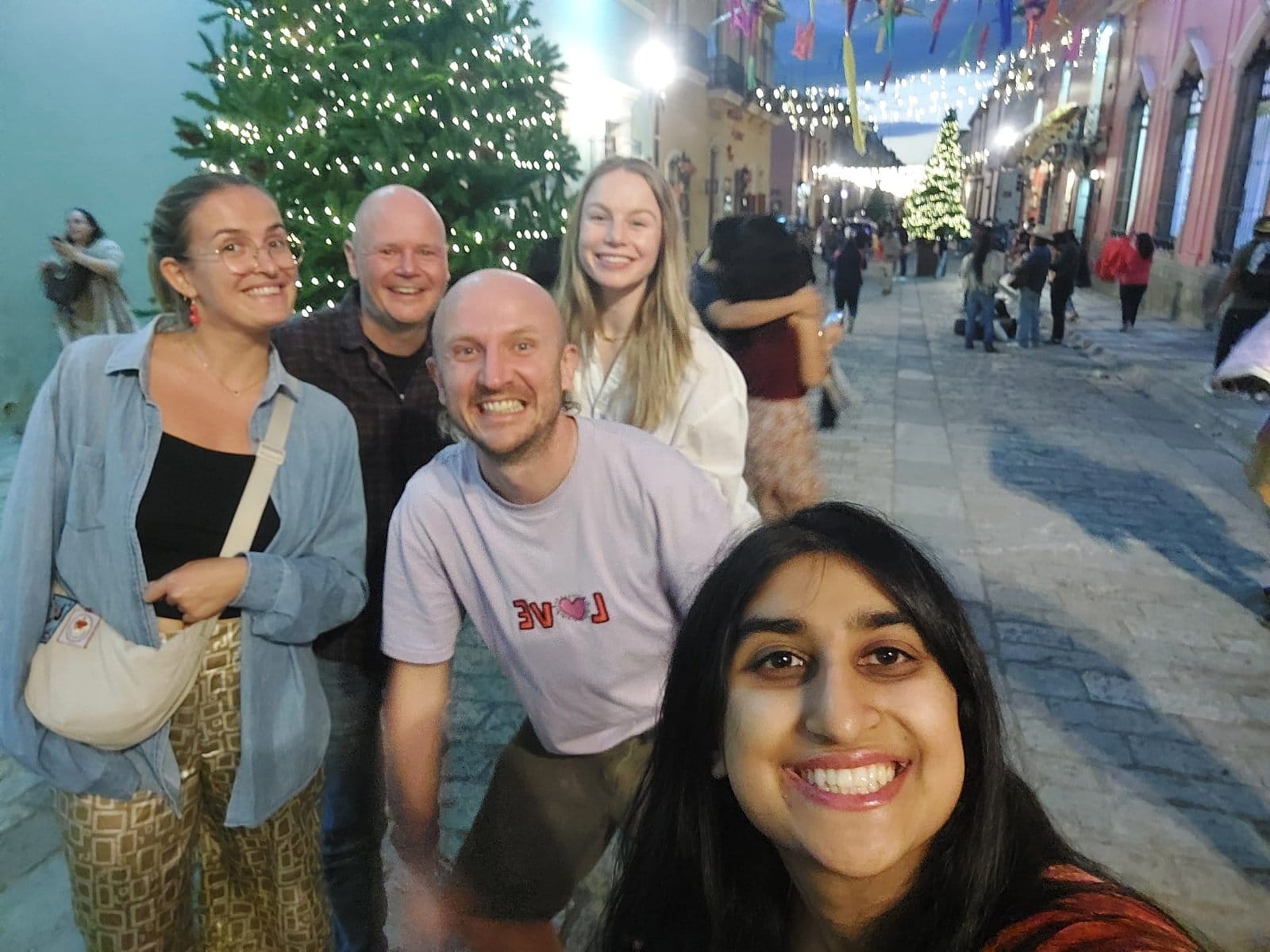 Co404 Oaxaca residents taking a group selfie on Oaxaca festive street with Christmas lights and decorations