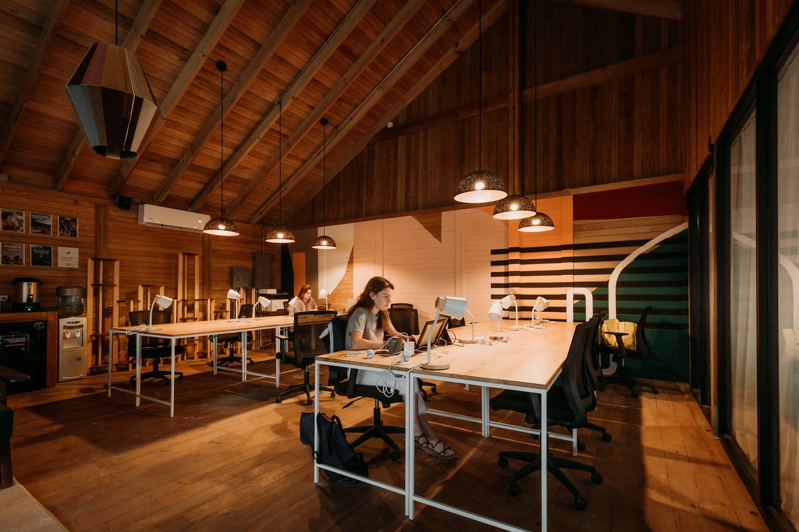 Residents working at dedicated desks in the coworking space at Selina Isla Mujeres inside the wooden A-frame building
