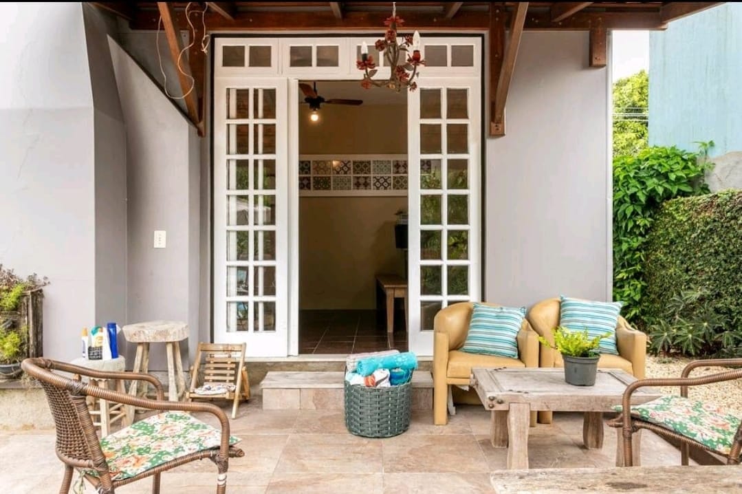 Covered patio lounge with sofa seating and French doors opening to the tiled common room at Coliving Casa Jerivá