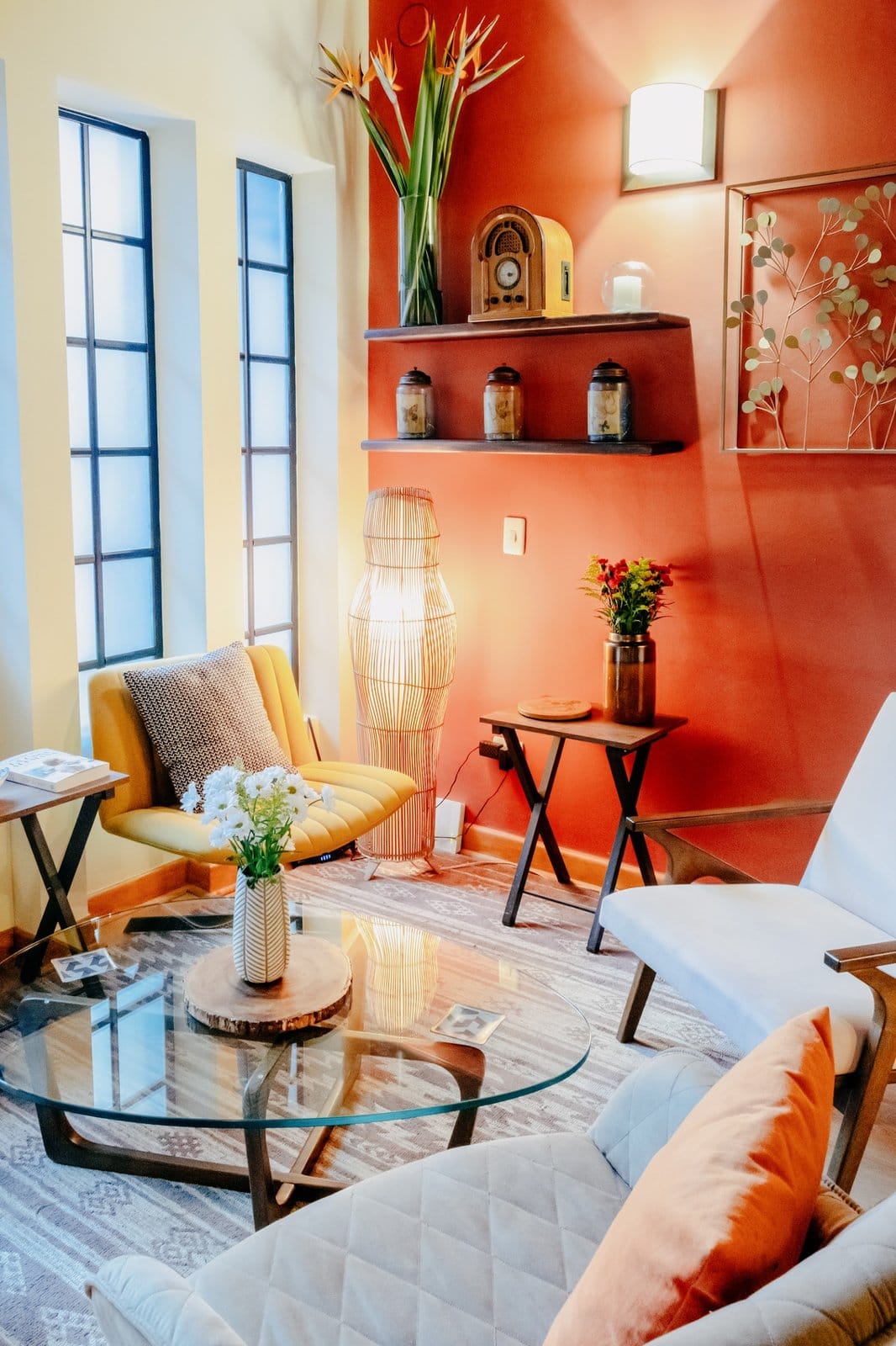 Cozy shared lounge with armchairs, glass coffee table and terracotta accent wall at Balu Coliving Medellin