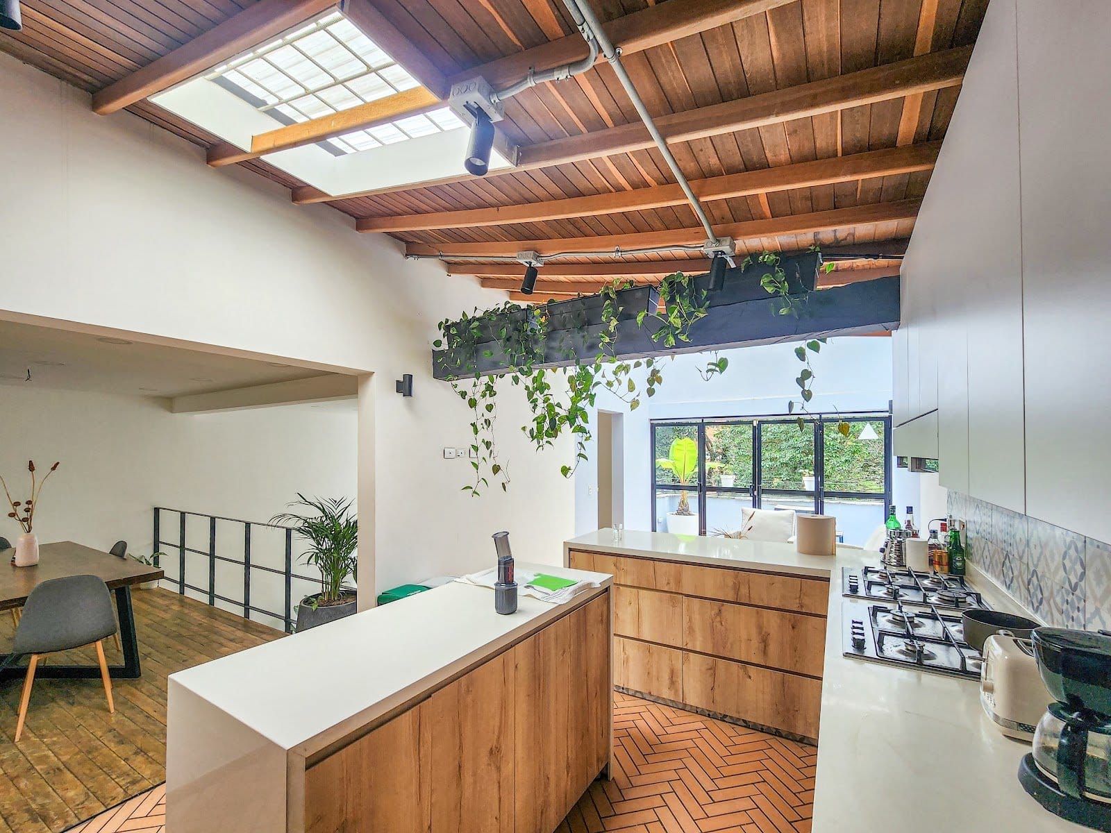 Bright open kitchen with wood-beam skylight and hanging plants at Outsite Medellín