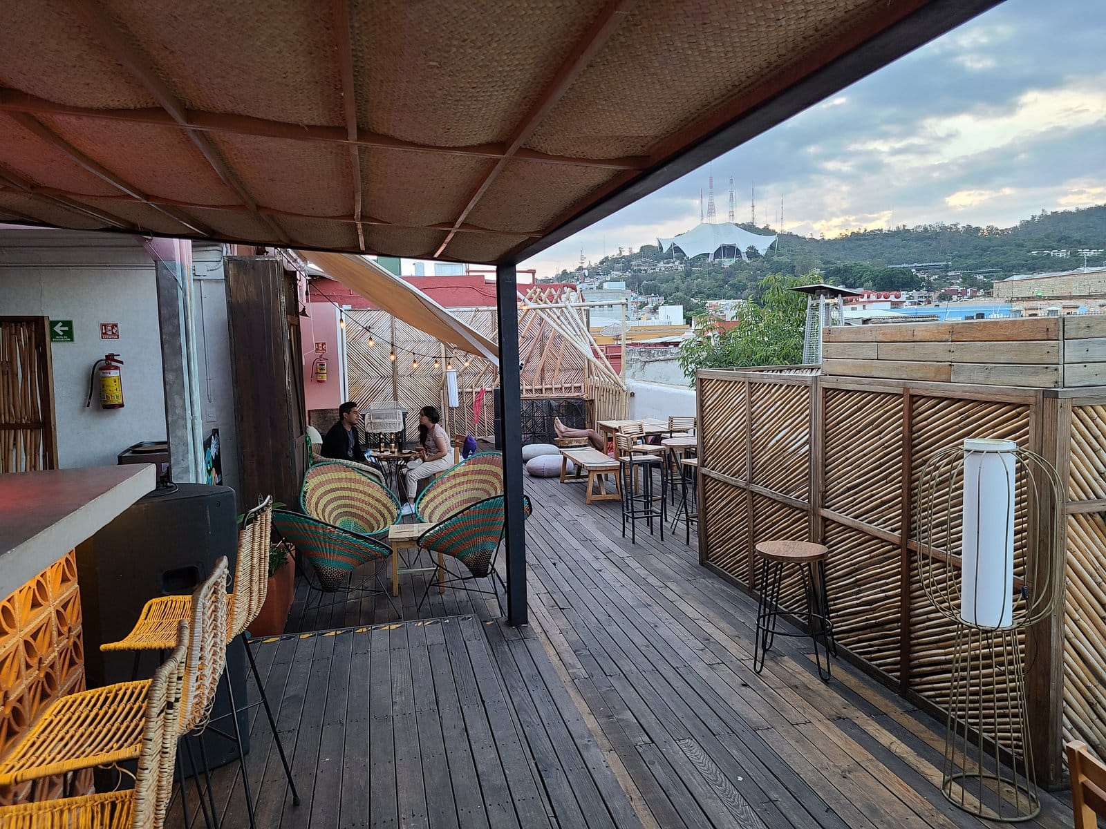 Two guests chatting on the rooftop terrace at Selina Oaxaca with woven chairs and city views