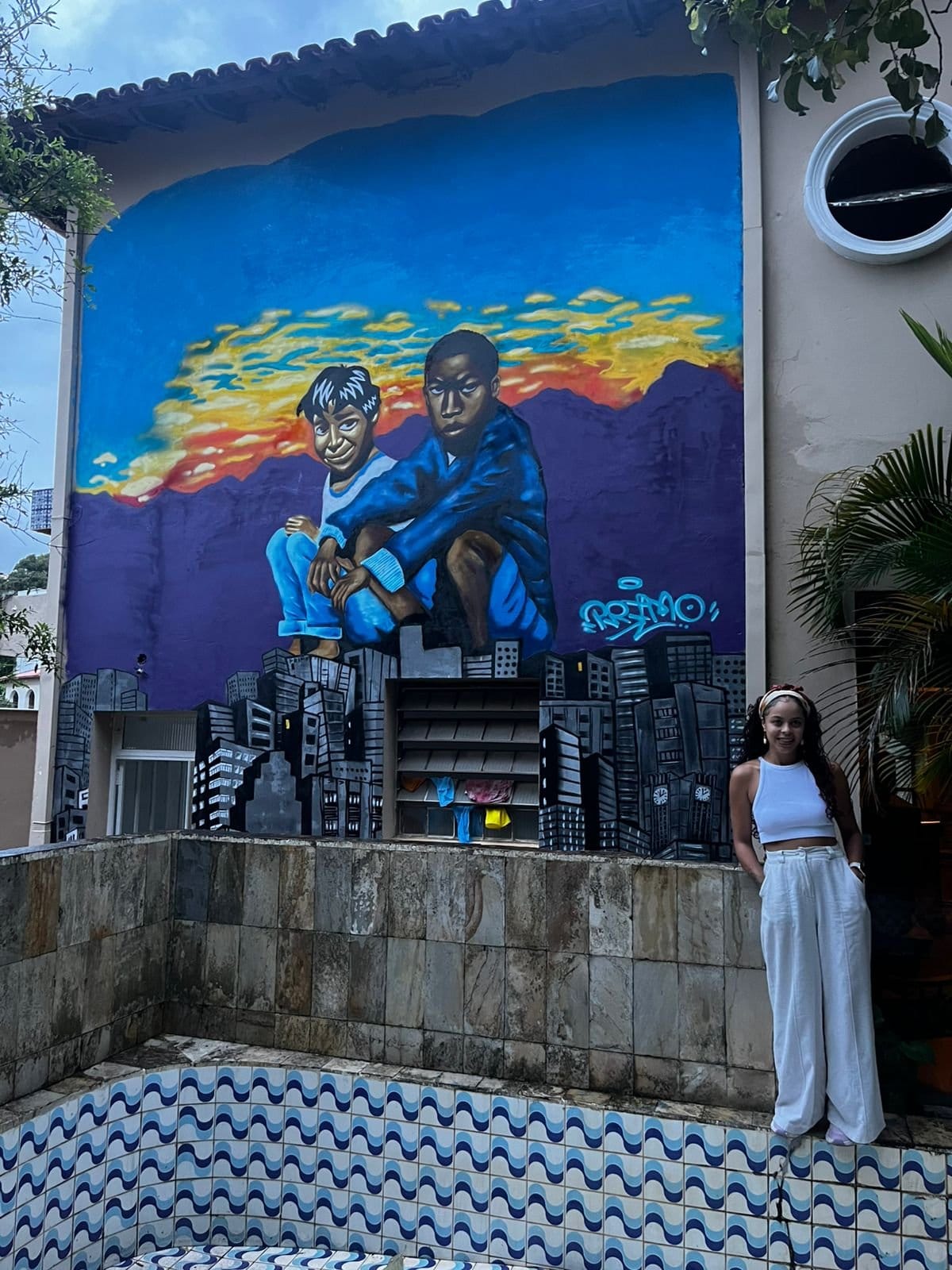 Resident relaxing by the colorful courtyard mural at Horizonte Coliving