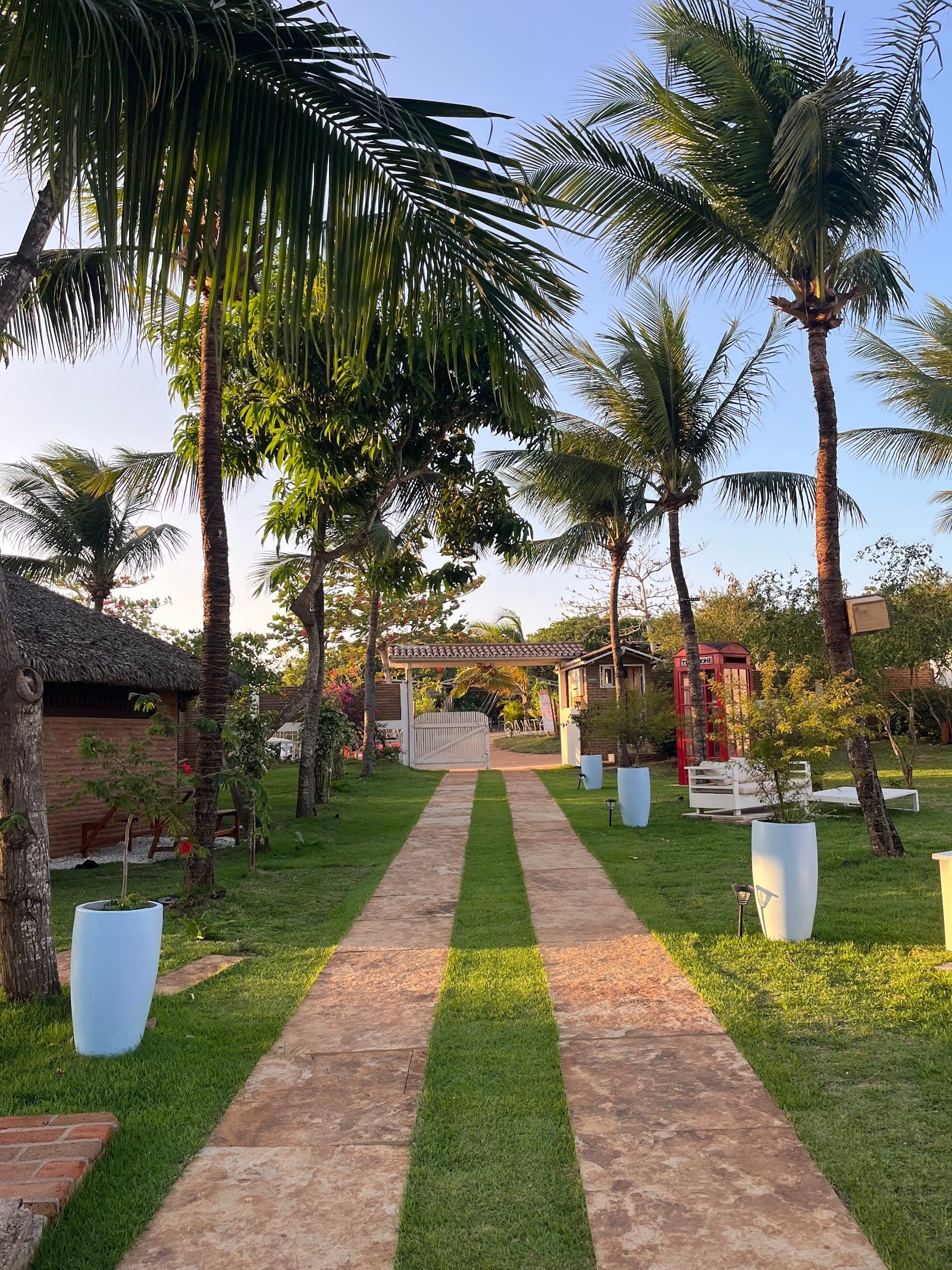 Guest strolling the palm-lined garden path among planters at FlowHouse Jeri