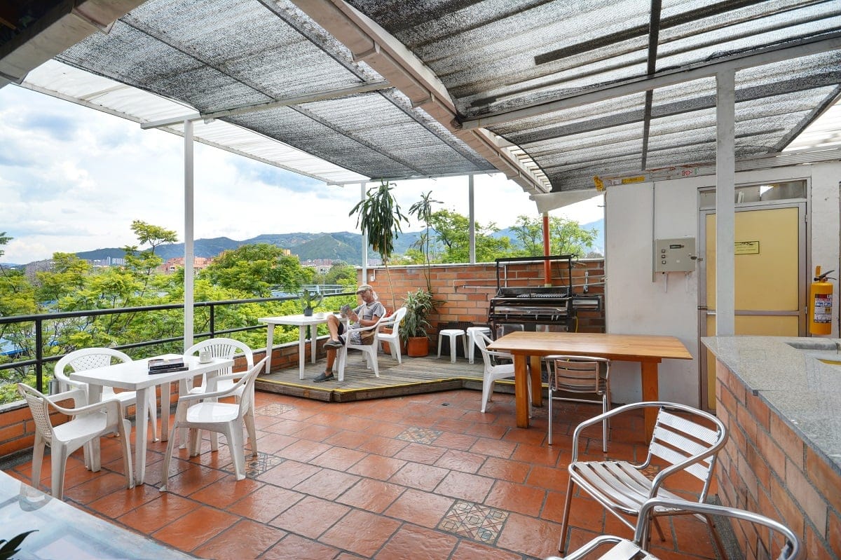 International House Co-Living covered terrace with seating where a resident relaxes against the green Medellin hillside