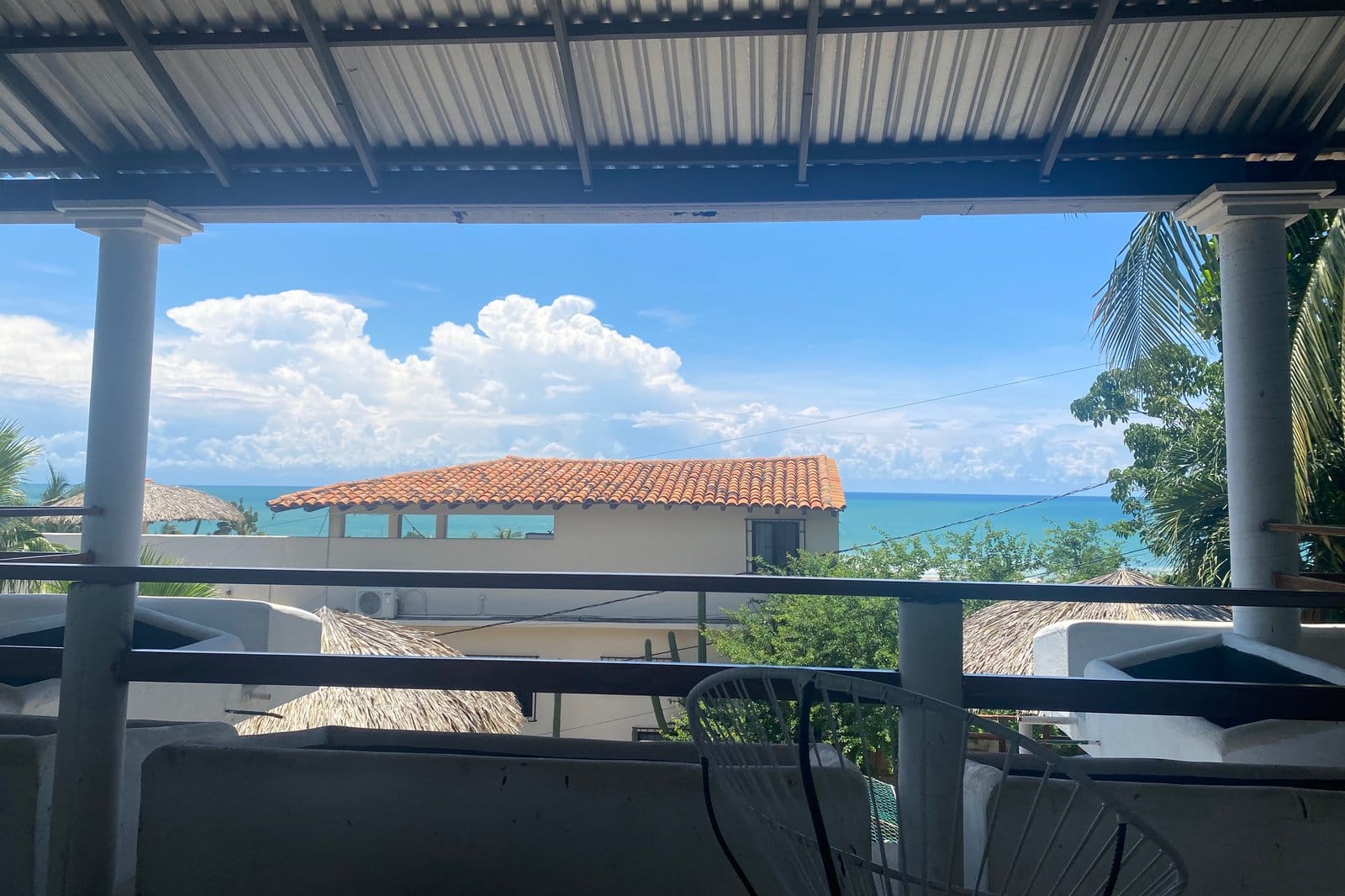 Covered upper terrace at Flow Coliving with white columns and Pacific Ocean view