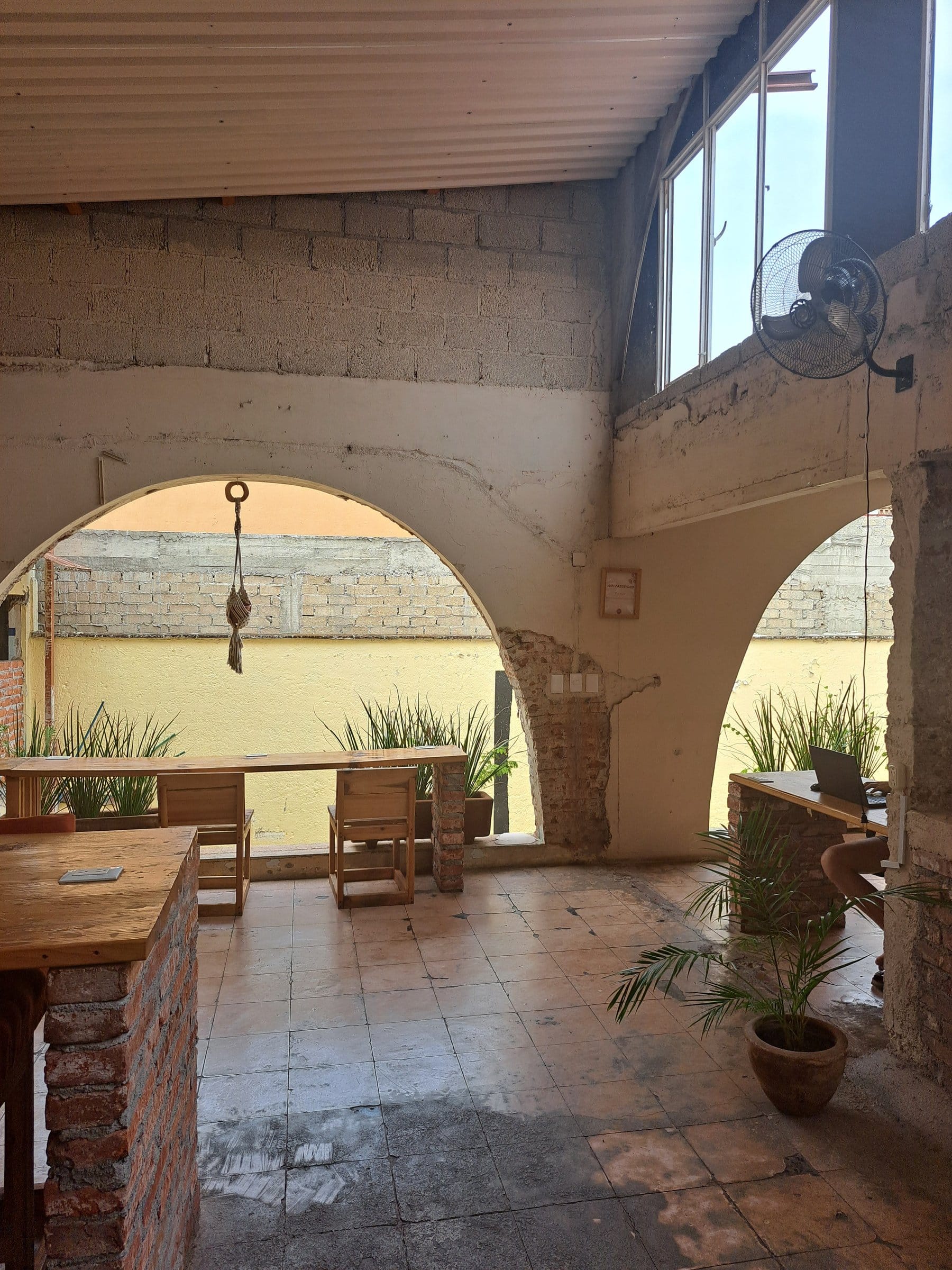 Co404 Oaxaca coworking space with high ceilings, brick arched openings onto courtyard, wooden desks, and natural light