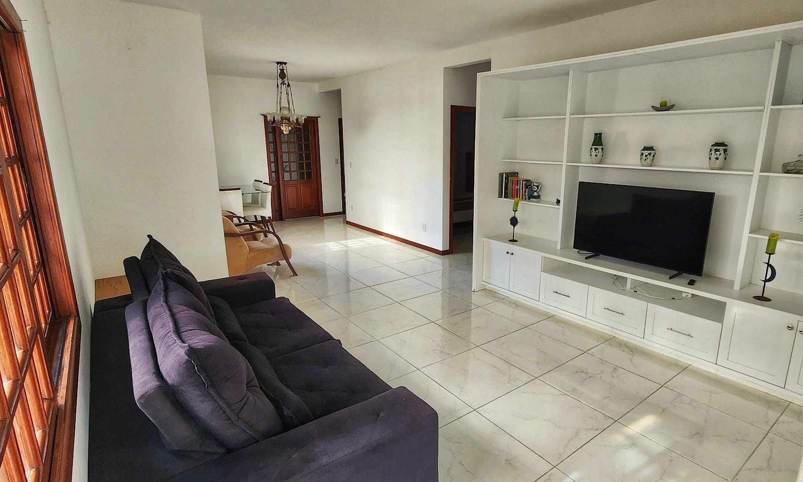 Bright open-plan living room with sofa and TV at Casa Maré coliving in Florianópolis