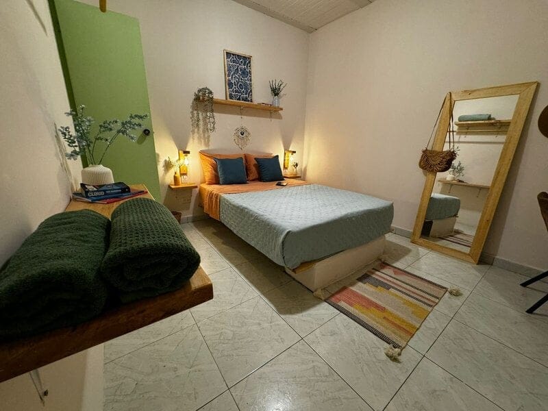 Stylish private bedroom with green accent wall, warm lighting and full-length mirror at Co404 Medellin