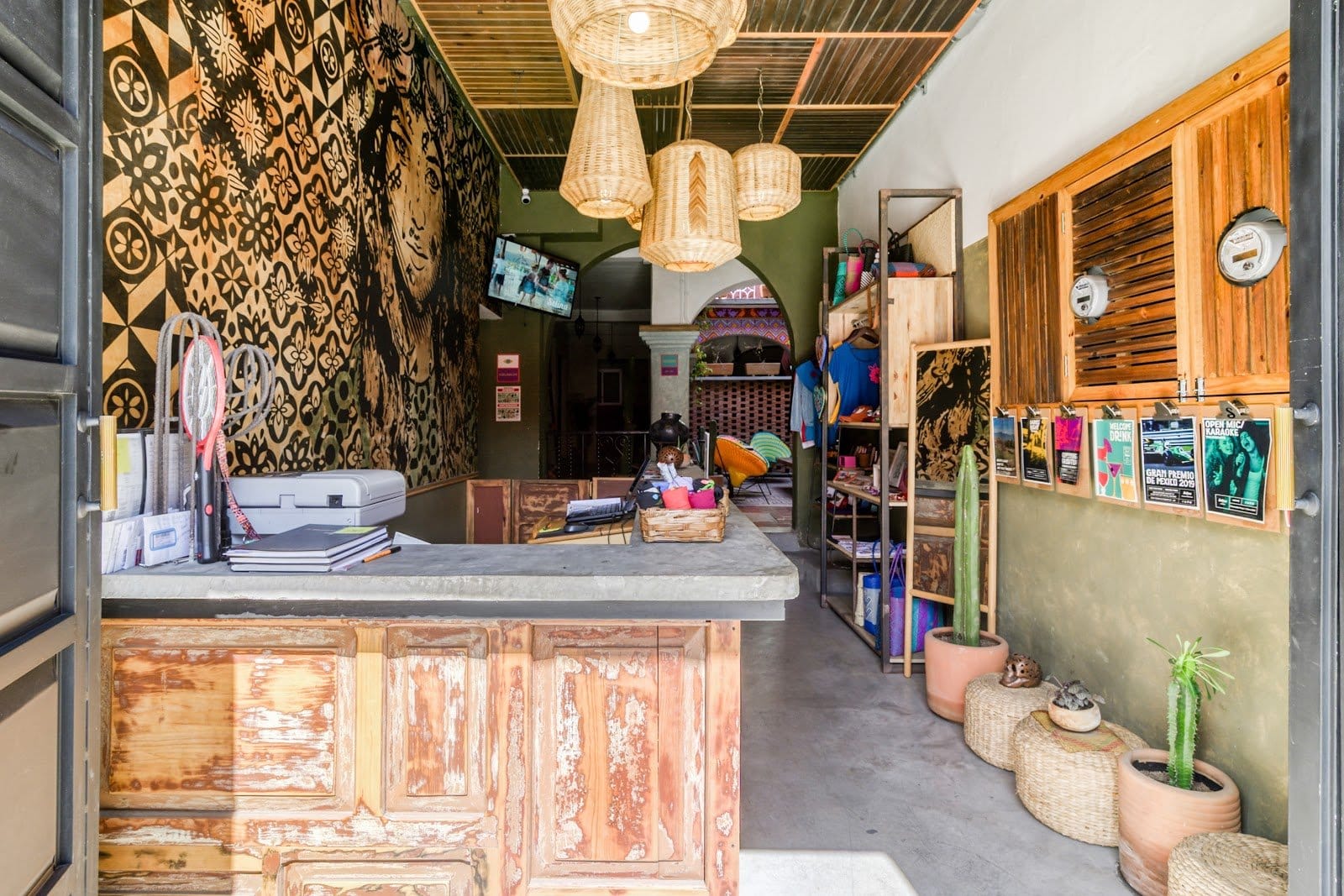 Eclectic reception and common lounge area at Selina Oaxaca with rustic wooden desk, hanging basket lamps, and vibrant Oaxacan decor