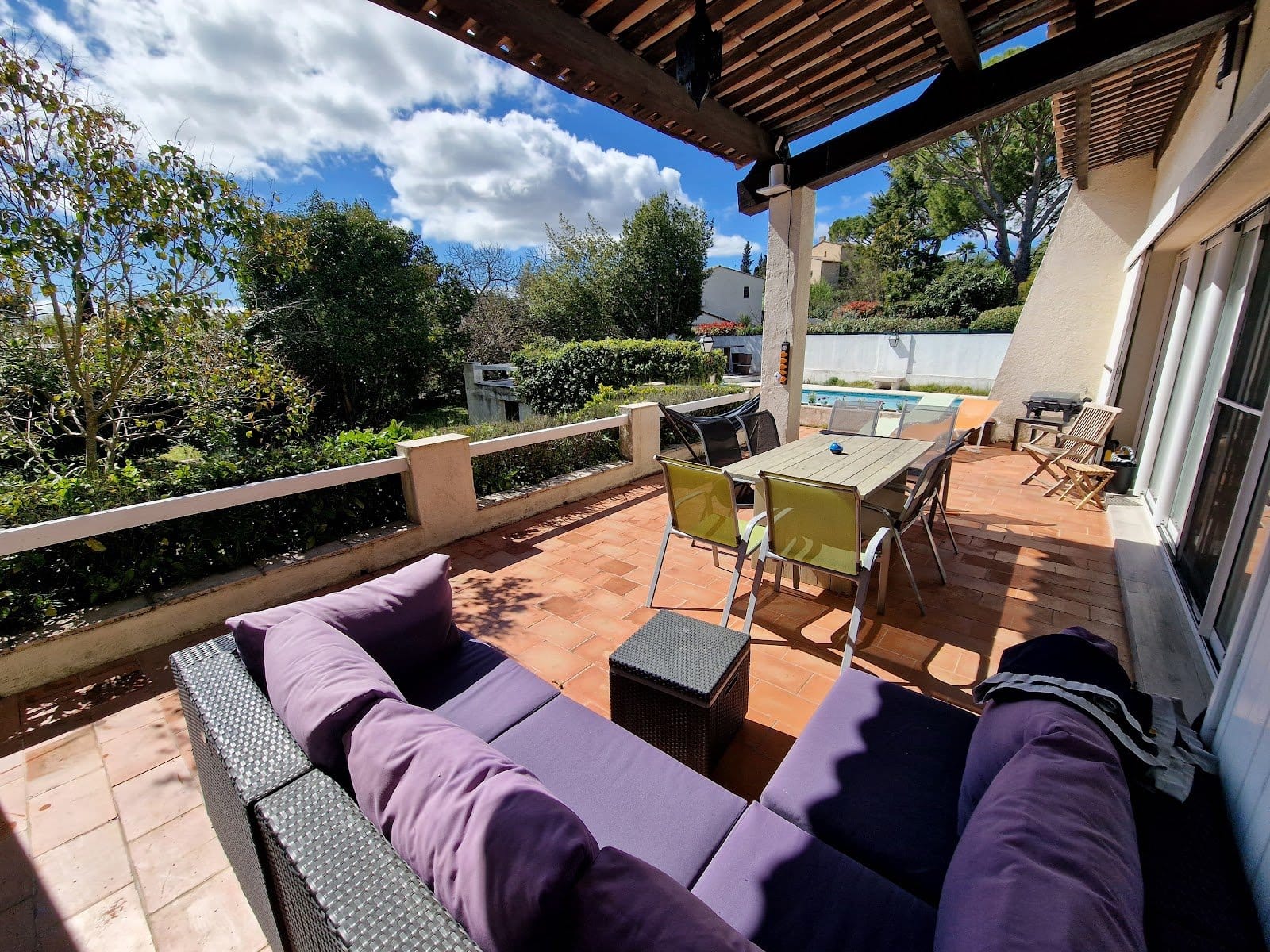 Large two-story house with pool and patio furniture under clear blue sky.
