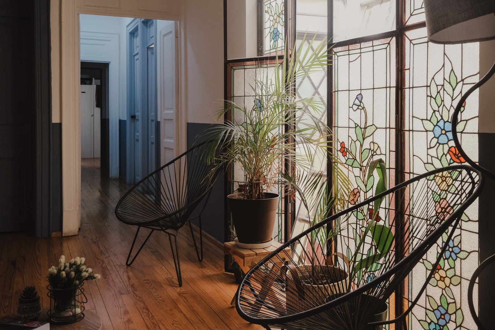Art nouveau stained glass window at U-Co Roma with black Acapulco chairs and tropical plants