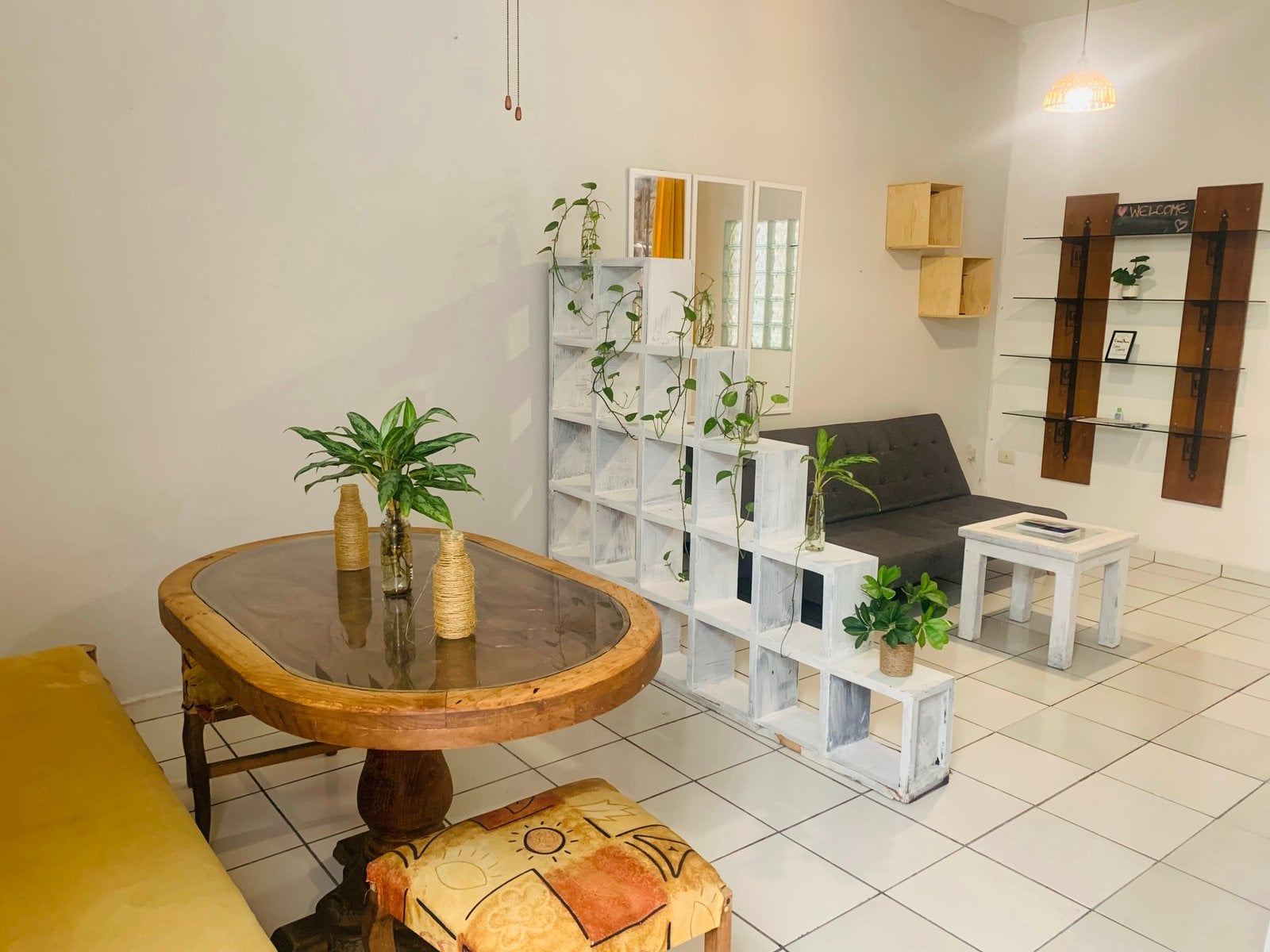 Common lounge area with wooden round table, plants and cubbies at Anana Coliving Playa del Carmen