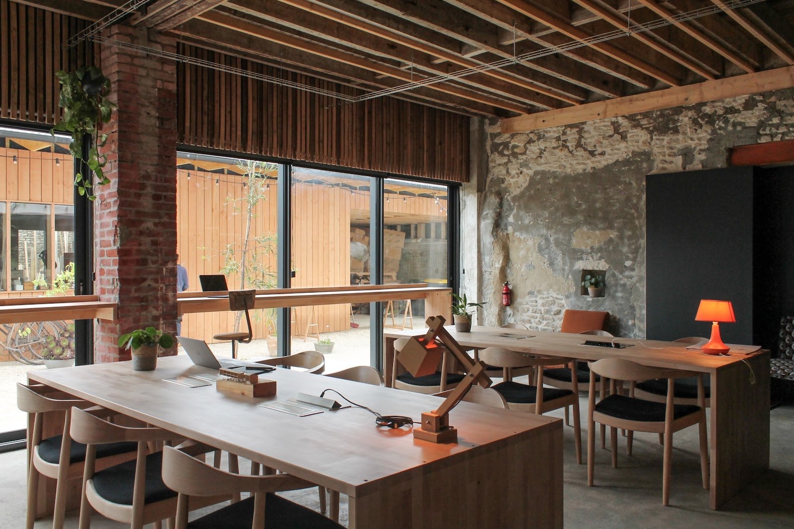 Spacious open room with wooden ceiling, sitting area and a small sleeping nook with visible bed and bedding.