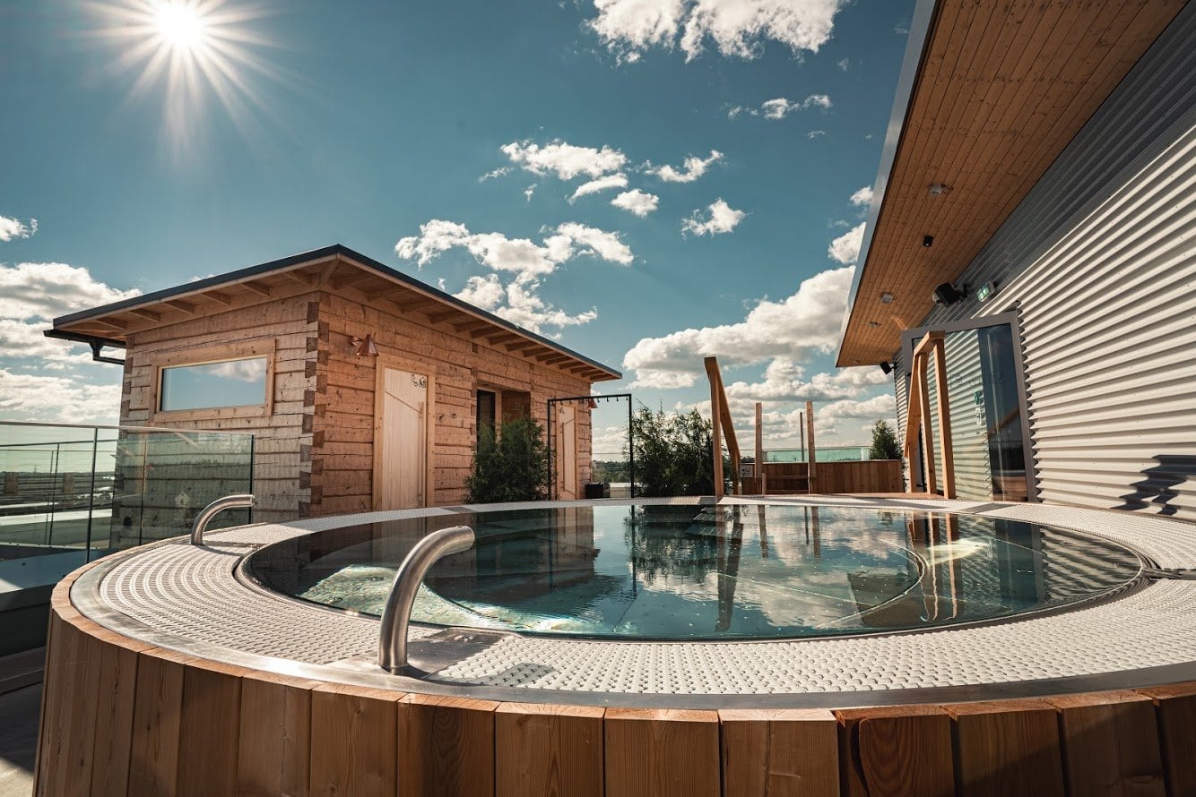 Rooftop plunge pool with wooden cabin structure and Helsinki skyline at VALO Hotel & Work under bright sun