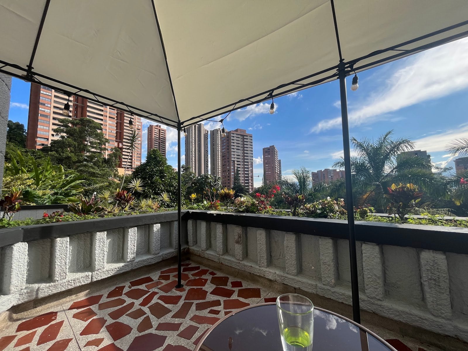 Rooftop terrace at Outsite Medellín with a gazebo, lush garden and Medellín city skyline view