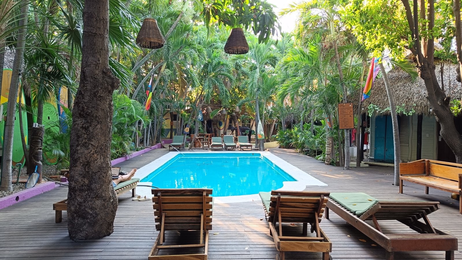 Lush tropical pool garden with wooden deck and lounge chairs at Selina Puerto Escondido