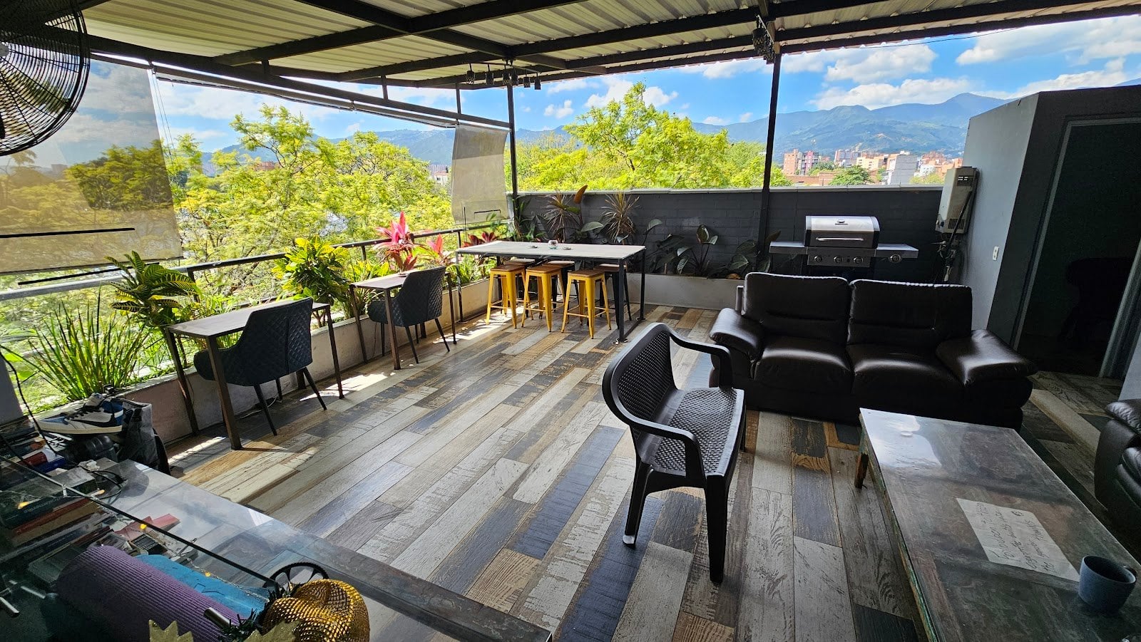 International House Co-Living rooftop terrace lounge with leather sofas, plants and panoramic Medellin mountain views
