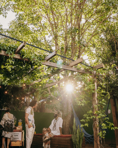 Lush garden with string lights and golden sunlight filtering through trees at Coliving Muní
