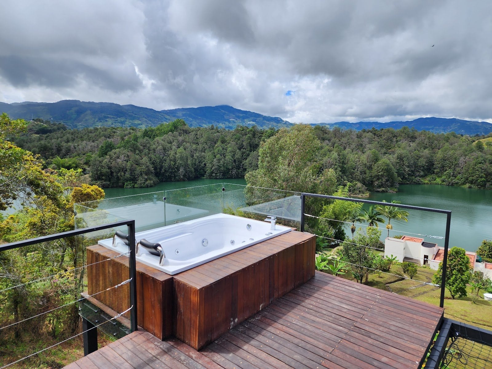 Wooden deck jacuzzi overlooking the lake and mountains at Riverside ecoliving Guatapé
