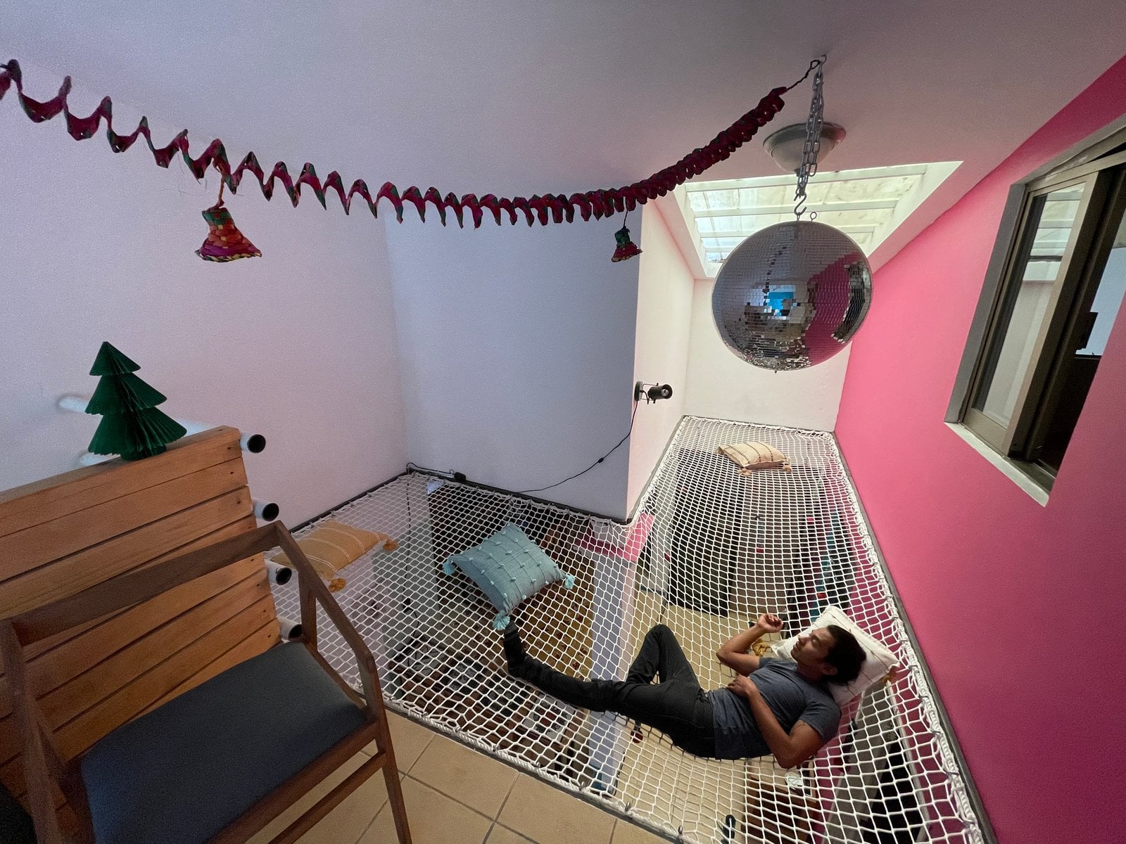 Person relaxing on rooftop net hammock at Aldea Tuya with disco ball overhead